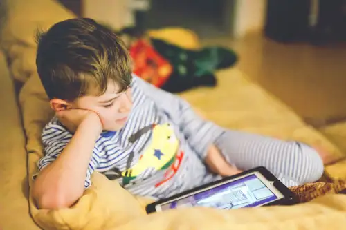 A relaxed boy using a tablet on a couch