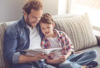 A father and son read a book together